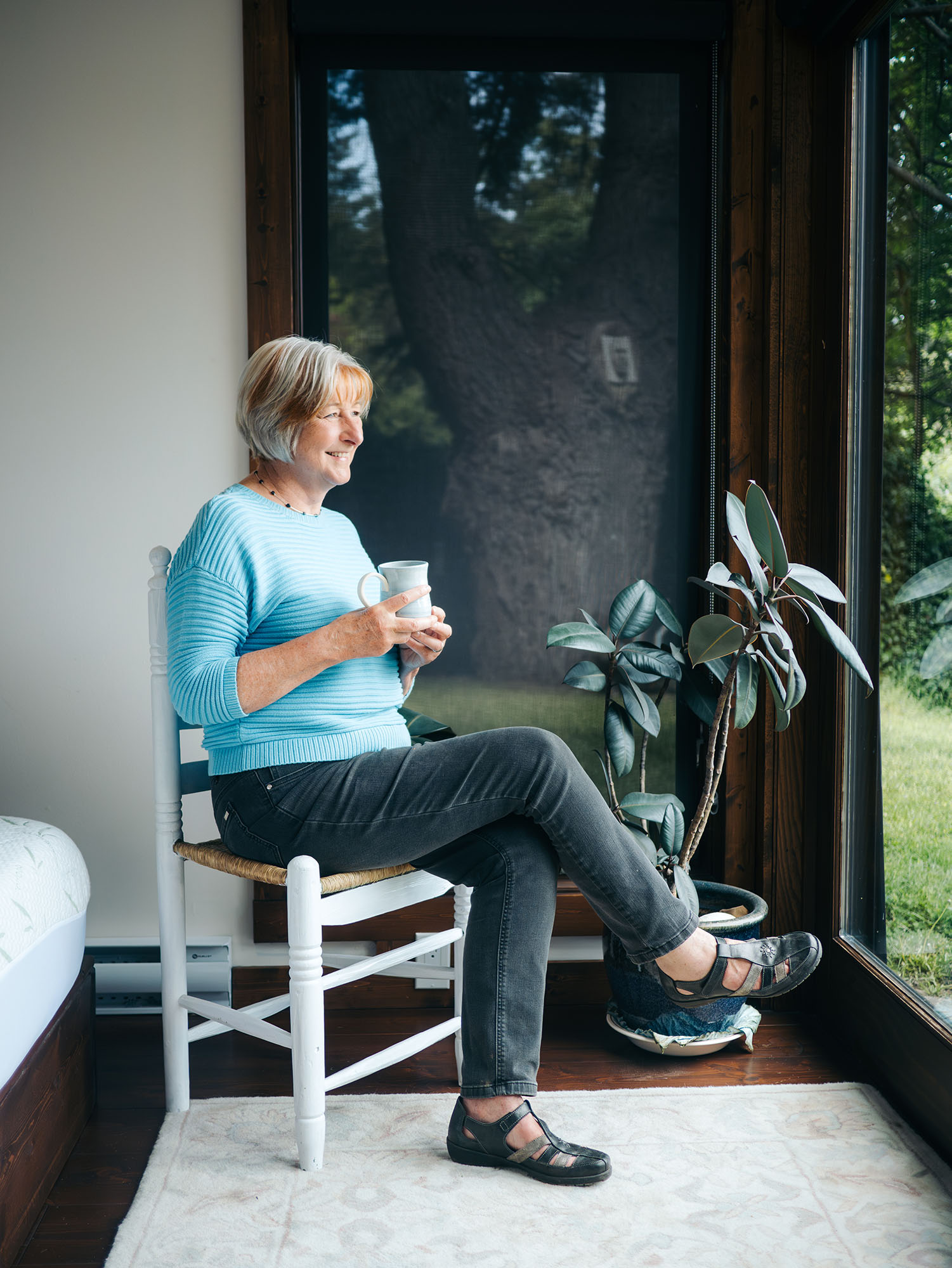 Anne Kaye sitting, looking outdoors at the views of Pender island